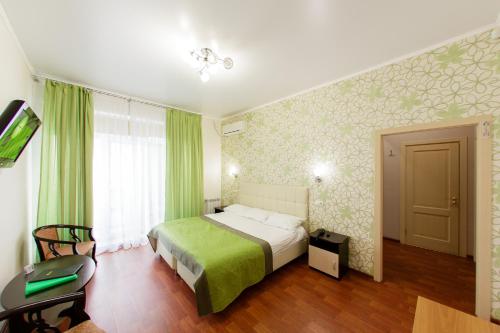 a bedroom with a bed with a green blanket at Lime Hotel in Khabarovsk