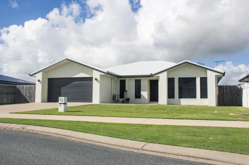 a white house with a garage on a street at Family Friendly Holiday Home in Mackay