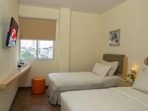 a hotel room with two beds and a window at d'primahotel ITC Mangga Dua in Jakarta