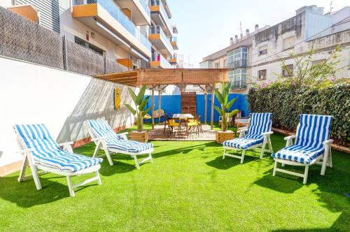 a patio with three chairs and a table on the grass at The Beach House Paradise by Hello Homes Sitges in Sitges