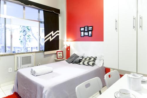 1 dormitorio con cama blanca y pared roja en Flat a Beira Mar - Copacabana, en Río de Janeiro