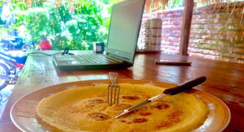 a plate with a fork and knife on a table with a laptop at Chemel Homestay in Kuta Lombok