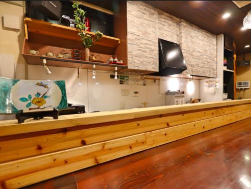 a long wooden counter in a room with a kitchen at BETTEI Yamashiro (別邸 山代) in Kaga