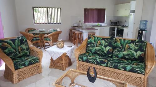 uma sala de estar com um sofá, cadeiras e uma mesa em Te Vaiora Villa em Rarotonga