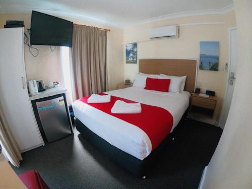 a hotel room with a large bed with red pillows at Huskisson Beach Bed and Breakfast in Huskisson