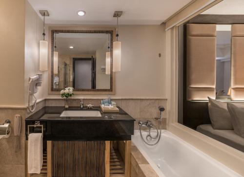 a bathroom with a sink and a tub and a mirror at Henann Garden Resort in Boracay