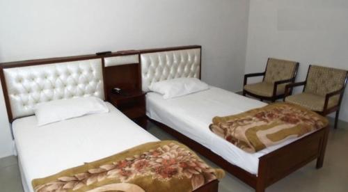two beds in a room with two chairs at Solo Hotel & Restaurant in Sargodha