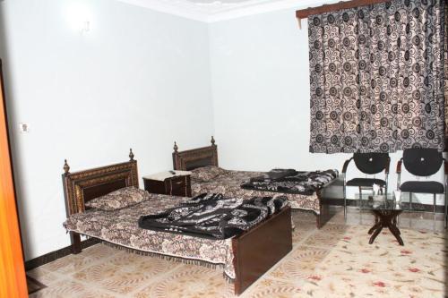 Un dormitorio con dos camas y una mesa y sillas. en Tulip Guest House Abbottabad, en Abbottābād