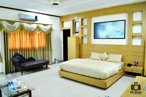 1 dormitorio con 1 cama, 1 silla y TV en The First Hotel, en Multán