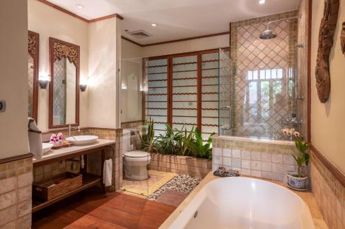 a bathroom with a tub and a toilet and a sink at Ariyasom Villa in Bangkok