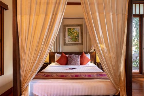 a bed with curtains and pillows in a bedroom at Ariyasom Villa in Bangkok