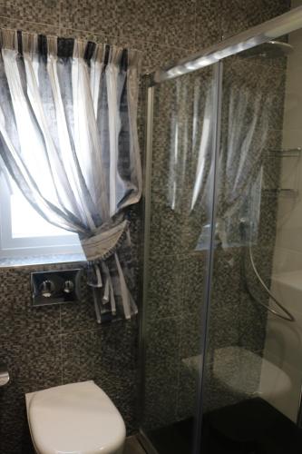 a bathroom with a shower and a toilet and a window at Seaside Apartments in Marsaskala