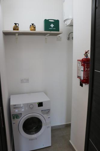 a washing machine in a bathroom with a shelf above it at Seaside Apartments in Marsaskala