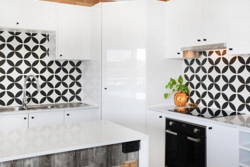 a kitchen with white cabinets and a black and white patterned wall at Illawong Apartment 7 in Mooloolaba
