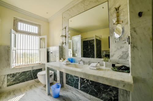 y baño con lavabo, aseo y espejo. en Bujera Fort, en Udaipur