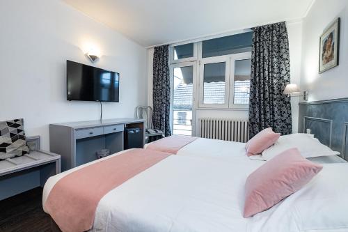 a hotel room with two beds and a flat screen tv at The Originals City Hotel de l Ange Guebwiller in Guebwiller