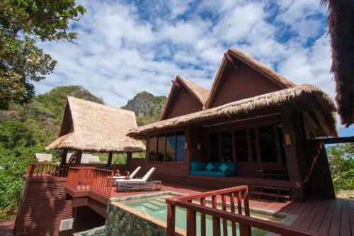 a house with a thatched roof and a deck at Cauayan Island Resort and Spa in El Nido