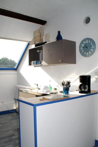 une cuisine avec un comptoir et une horloge au mur dans l'établissement Studio meublé Jacynthe Proche Le Havre - Etretat - Honfleur, à Saint-Romain-de-Colbosc