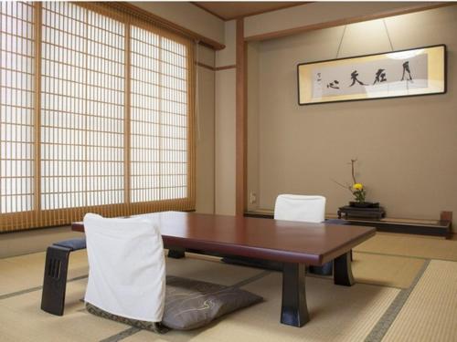 a dining room with a wooden table and white chairs at Gingetsu in Shimo-suwa