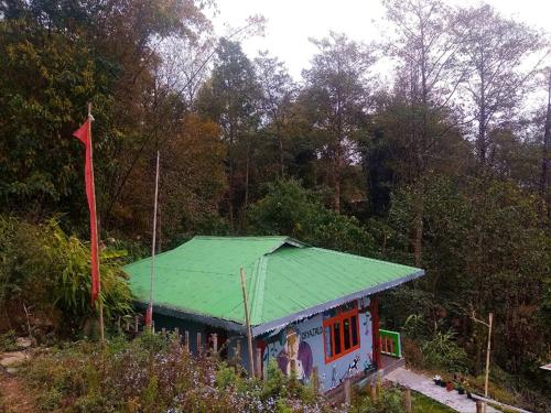 a small house with a green roof and a flag at VAMOOSE PARKHA SIKKIM in Rangli