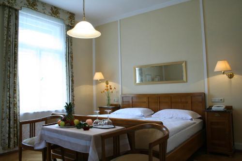 a bedroom with a bed and a table and a window at Hotel Villa Westend in Merano