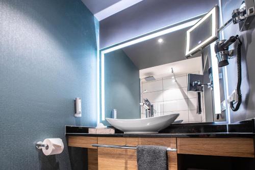 a bathroom with a sink and a large mirror at Leoso Hotel Leverkusen in Leverkusen