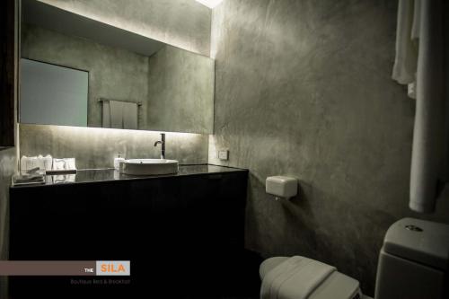 a bathroom with a sink and a mirror and a toilet at The Sila Boutique Bed & Breakfast in Chiang Mai