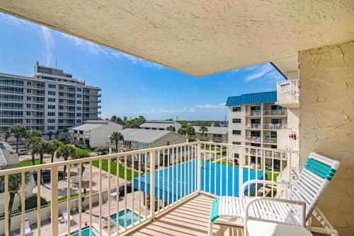 een balkon met 2 stoelen en een zwembad bij Atlantic Avenue Condos in New Smyrna Beach