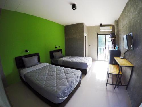 a room with two beds and a green wall at Rimnamresidence in Ban Muak Lek
