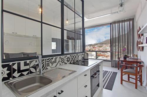 uma cozinha com um lavatório e uma grande janela em Harbour View Apartments em Cidade do Cabo