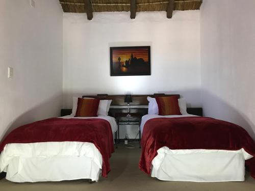 um quarto com 2 camas com lençóis vermelhos e brancos em Greenwoods Self-Catering em Pretoria