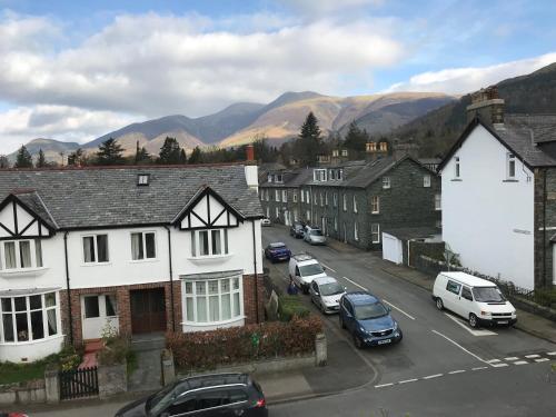 a town with cars parked on a street with mountains at Winchester House in Keswick