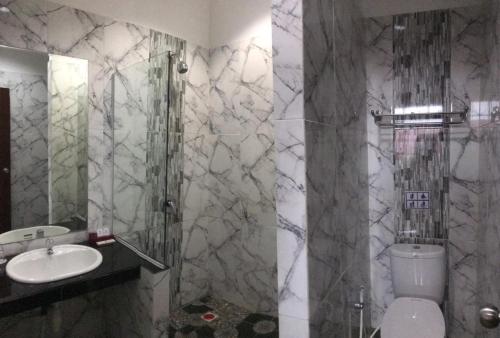 a bathroom with a sink and a shower and a toilet at Hotel Harmony In & Karaoke in Pontianak