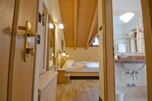 La salle de bains est pourvue d'un lavabo et d'un lit dans la chambre. dans l'établissement Hotel Daniela, à Livigno