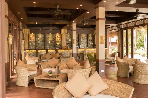 a lobby with wicker chairs and tables and windows at Cauayan Island Resort and Spa in El Nido