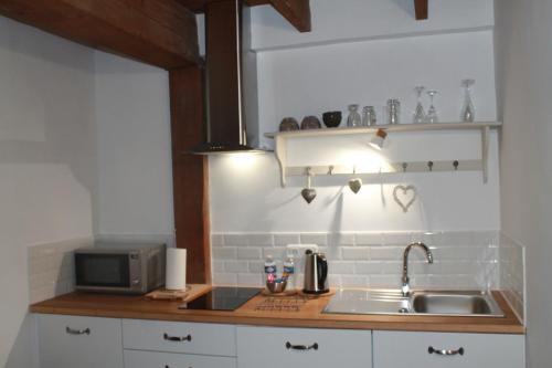 a kitchen with a sink and a microwave at Chambre du Rouard LE RUISSEAU in Camiers