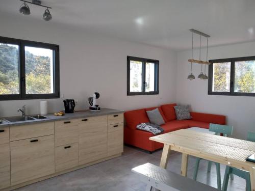 Una sala de estar con un sofá rojo y una mesa. en Casa Vilallonga, en Villelongue-dels-Monts