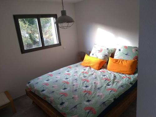 Un dormitorio con una cama con almohadas naranjas y una ventana. en Casa Vilallonga, en Villelongue-dels-Monts