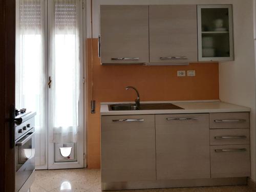 una cucina con armadi bianchi e lavandino di Appartamento Azalea a Levanto
