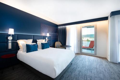 a hotel room with a large bed and a balcony at Hôtel Mercure Toulon La Seyne-Sur-Mer in La Seyne-sur-Mer