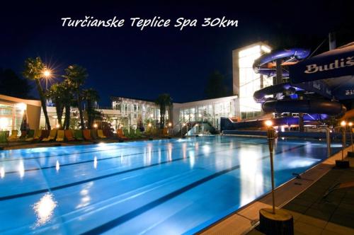 a large swimming pool at night with a building at Apartmán Katka in Sučany
