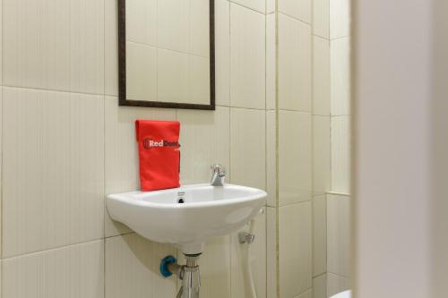un lavabo de salle de bain avec un miroir et une serviette rouge dans l'établissement RedDoorz near Puri Indah Mall, à Jakarta