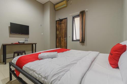 a bedroom with a bed with red and white sheets at RedDoorz near Puri Indah Mall in Jakarta