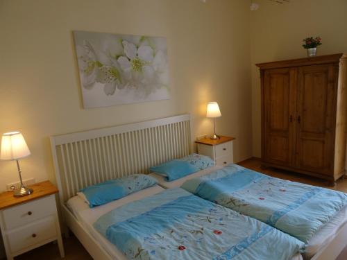 ein Schlafzimmer mit einem Bett mit blauer Bettwäsche und zwei Lampen in der Unterkunft Fürstenhof Fewo Grönland in Sassnitz