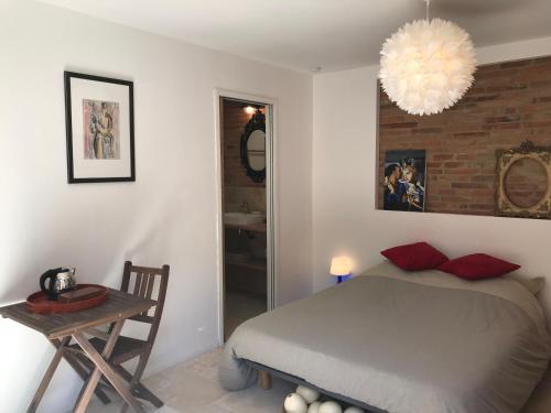 a bedroom with a bed and a table and a chandelier at La bulle de Gaston in Toulouse