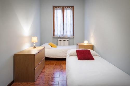 a bedroom with two beds and a dresser and a window at Casa Girasole in Bardolino