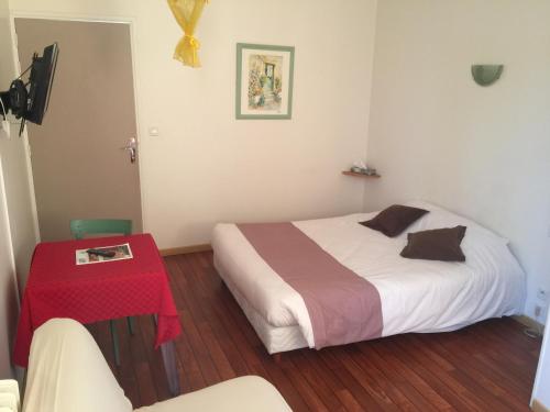 a bedroom with a bed and a red table at Au Père Tranquille in Tinchebray