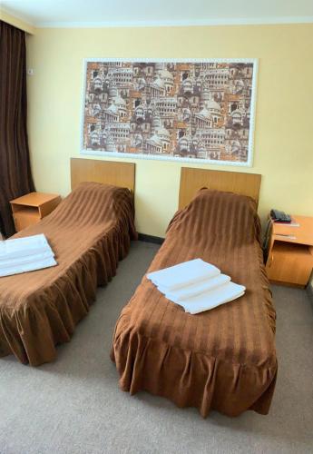 two beds in a hotel room with towels on them at Гостиница ИЛЕК in Aktobe