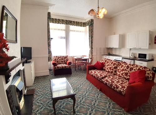 a living room with a red couch and a table at Rosemede Holiday Flats in Blackpool