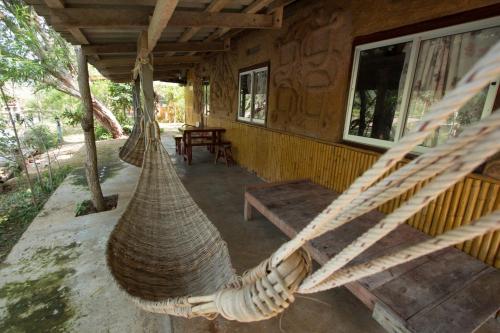 a porch of a log cabin with a hammock at Numpu Baandin in Sam Roi Yot